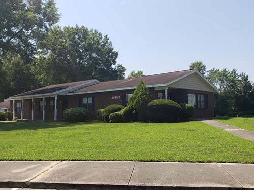 A house with a front porch sitting on a small hill.