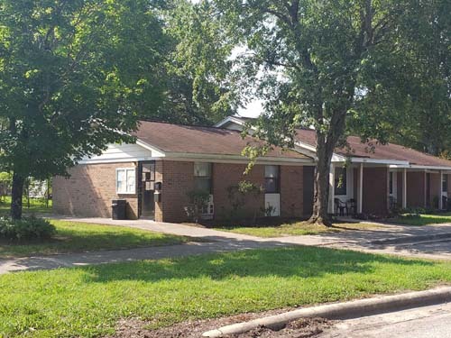 The side view of a house with many shade trees.