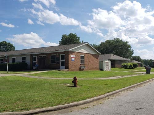 The street view of many housing units with a fire hydrant on the corner. 
