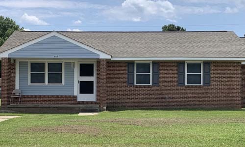 The front view of a brick house and its front yard.