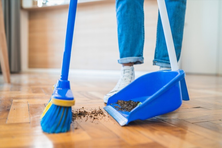 A person sweeping dirt into a dustpan.