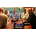 A group of men standing at a large wooden table visiting.