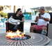 Two people sitting in front of an outdoor fireplace.