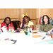 Three ladies sitting at a table listening to a presentation.