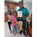  A woman holding a painting, and two children pose for a picture. 