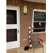  A brick house that has a gift wrapped door, along with lights, and a candy cane decoration on the front porch.  